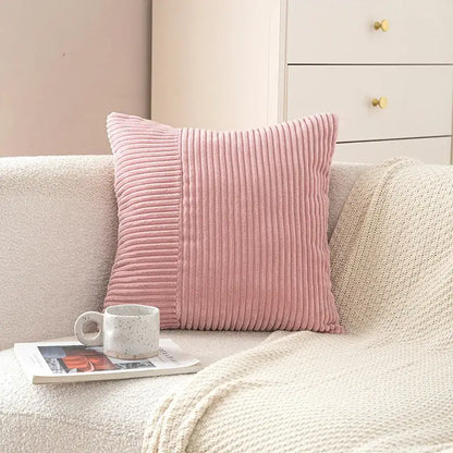 A soft pink pastel corduroy striped body pillow with vertical ribs resting on a cozy beige couch for lumbar support