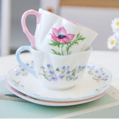 A delicate pastel floral porcelain coffee cup with pink handle and anemone design on a decorbites bone saucer set