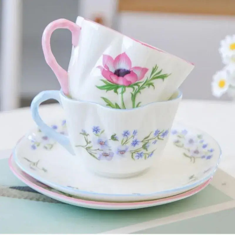 A delicate pastel floral porcelain coffee cup with pink handle and anemone design on a decorbites bone saucer set