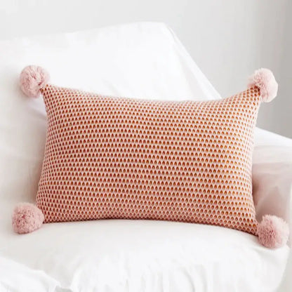A soft pink pastel knit pompom ball cushion cover with fluffy pom-poms for bedroom decor by decorbites knit pompom
