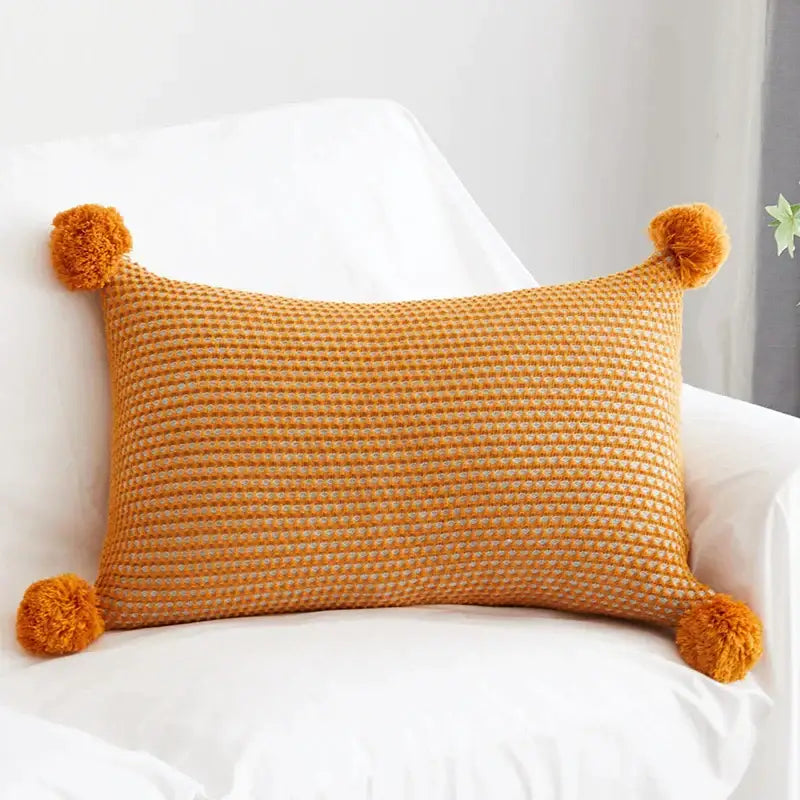 Warm orange waffle-knit cushion cover with fluffy pompom balls at each corner for decorbites knit pompom decor