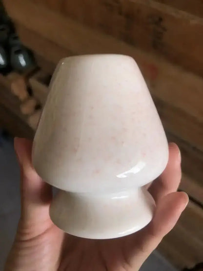 A smooth off-white ceramic matcha whisk stand with subtle speckled texture and classic tapered shape for tea bowl holder