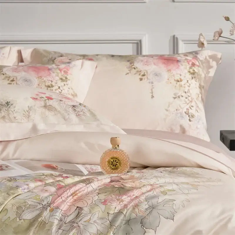 A delicate pearlescent perfume bottle with a golden cap on a pastel pink floral egyptian cotton bedding set duvet cover