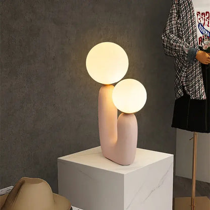 Pastel pink ceramic ball table lamp featuring dual glowing glass ball bulbs for bedroom use