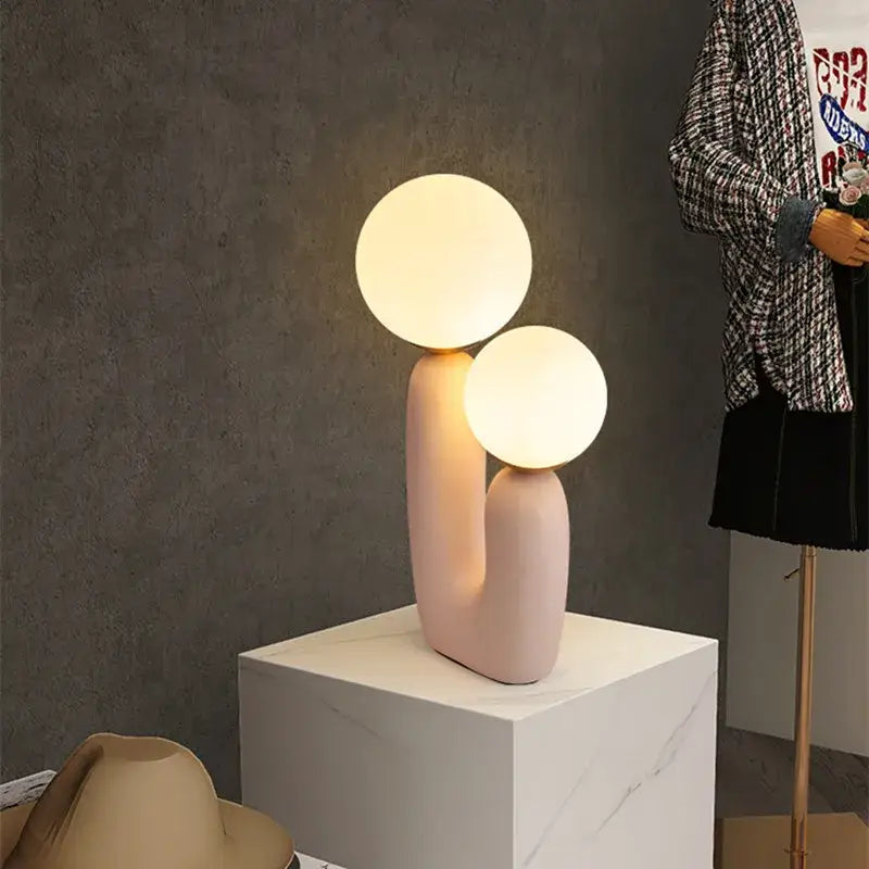Pastel pink ceramic ball table lamp featuring dual glowing glass ball bulbs for bedroom use