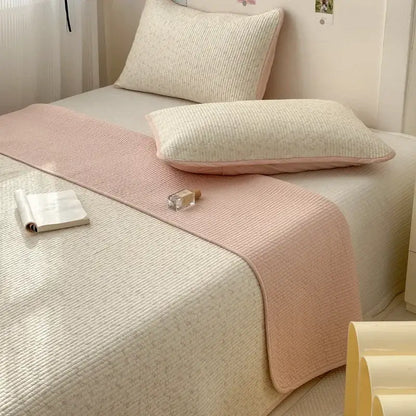 A soft pink and cream cotton bed cover with ribbed texture used as an anti-slip tatami mat bed runner