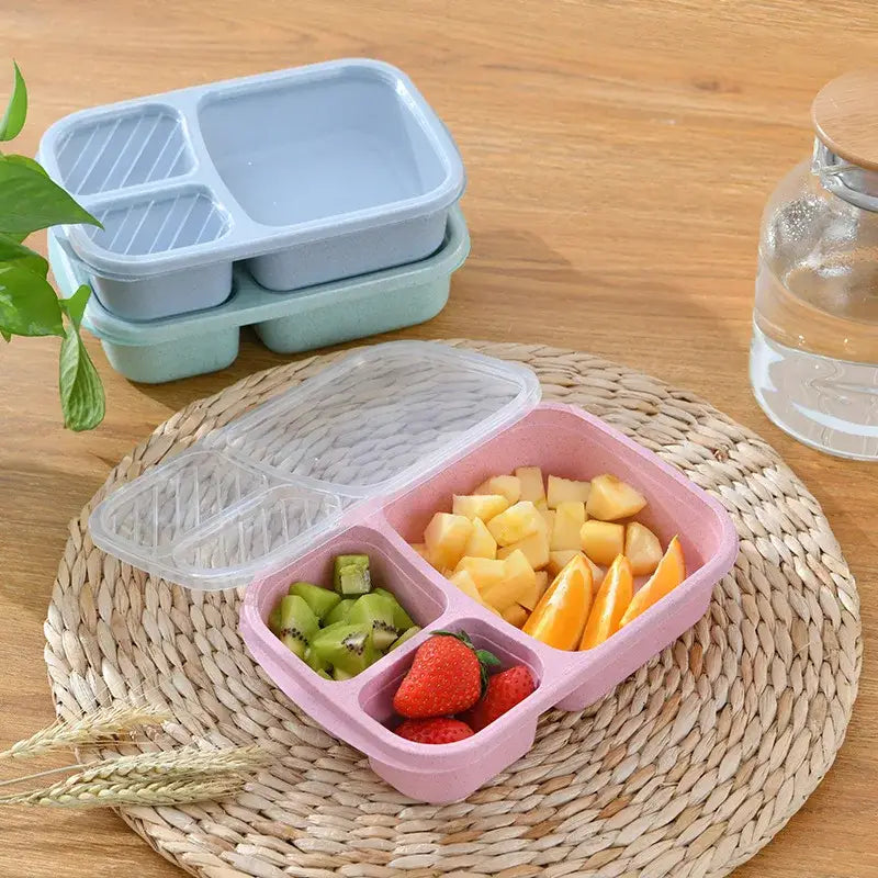 Pastel pink wheat straw bento box set with clear lid and three compartments filled with sliced fruit for kitchen use