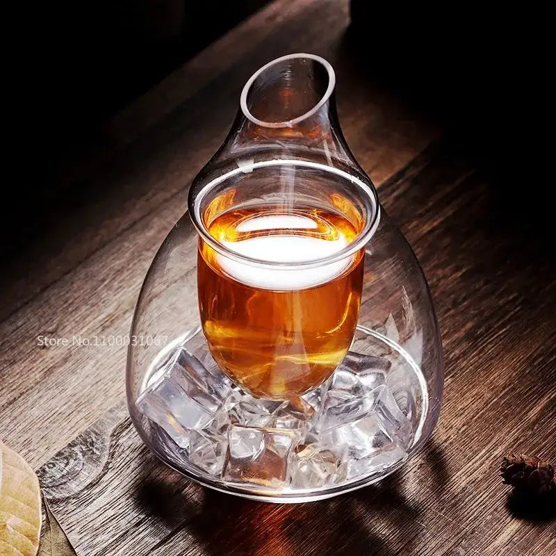 Pear shaped clear glass wine decanter with slender neck and bulbous base filled with amber liquid in ice jug set