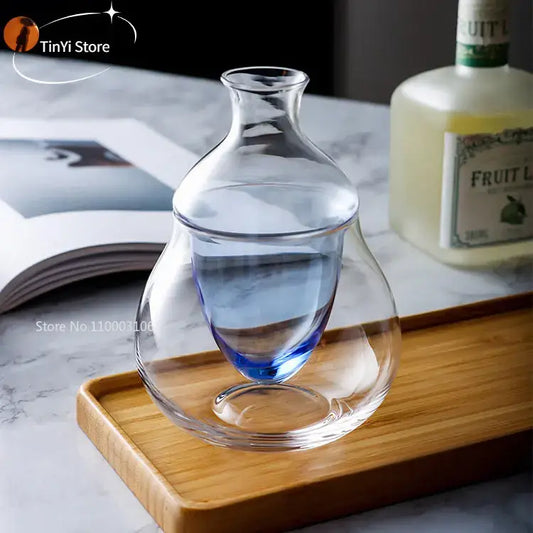 Clear glass wine decanter with pear-shaped body and blue tinted base on wooden tray ice jug set for dining room decor