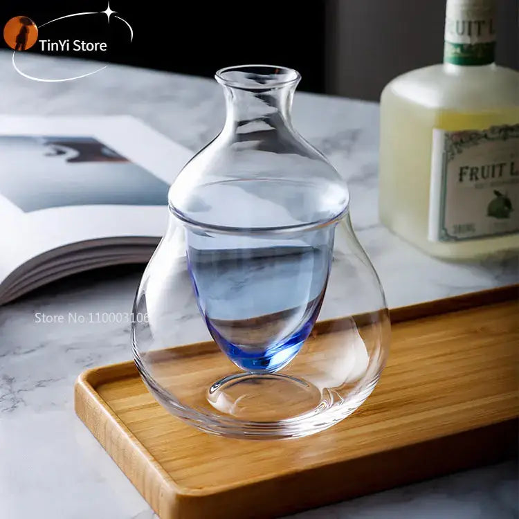 Clear glass wine decanter with pear-shaped body and blue tinted base on wooden tray ice jug set for dining room decor