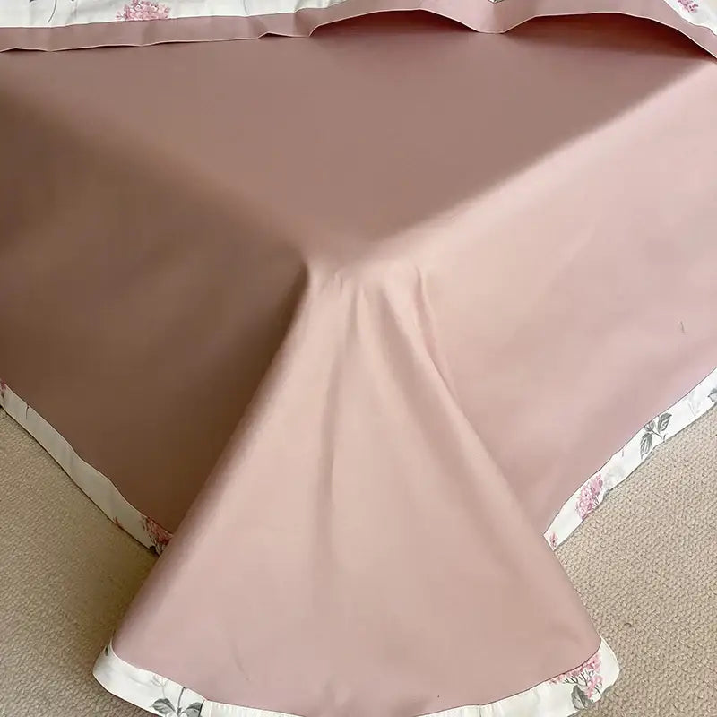 A soft blush pink satin bedspread with delicate floral edges in a pink and cream floral egyptian cotton print bedding set