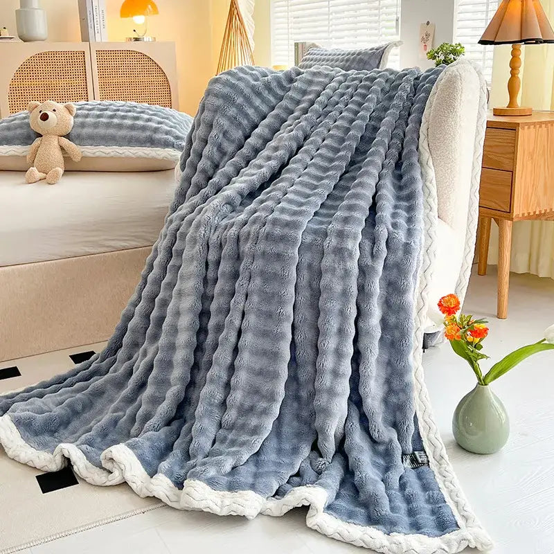 A plush light blue throw blanket with white braided border made of decorbites cozy faux rabbit fur for bedroom use
