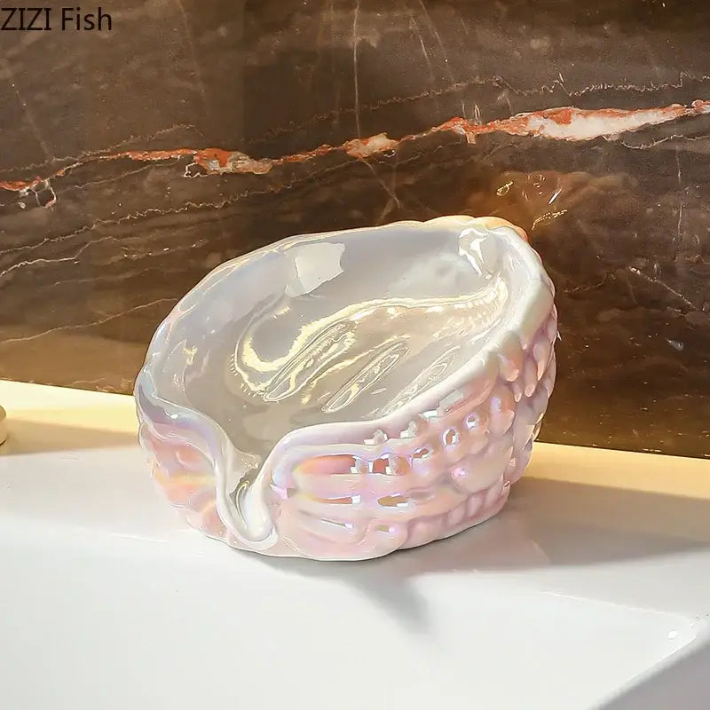 Delicate iridescent pink and yellow bitter gourd ceramic soap dish with textured shell exterior and smooth interior drainage rack