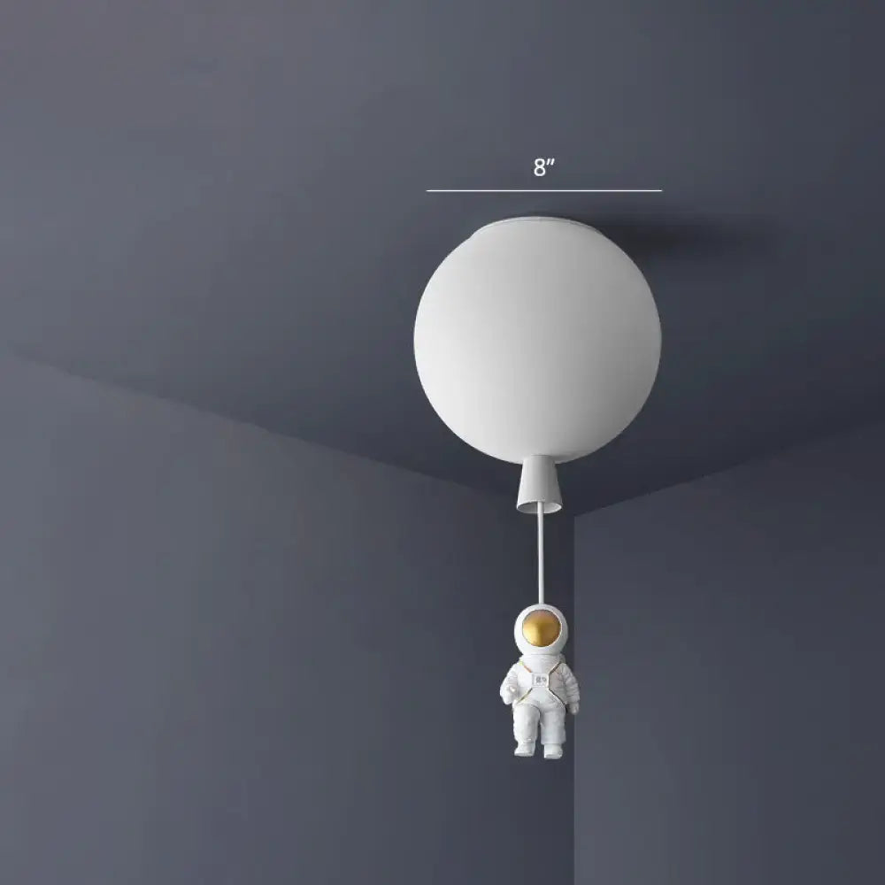 White spherical balloon-shaped ceiling lamp with a pink and blue miniature astronaut figure hanging below astronaut ceiling lamp