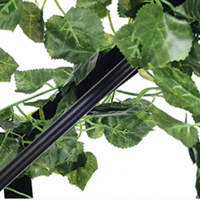 Black plastic support beam nestled among artificial green leaves in pink cherry blossoms green plants pendant light