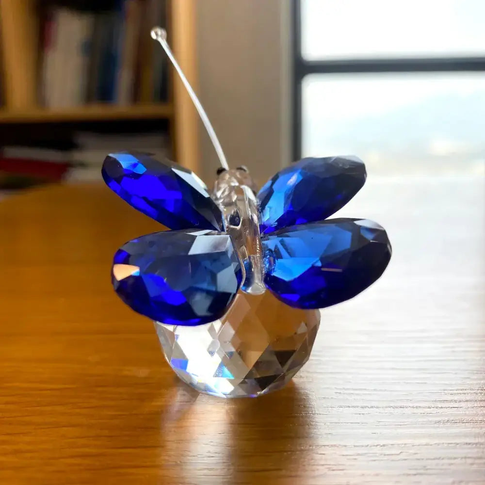 A sparkling blue crystal butterfly figurine with faceted wings and a clear multifaceted base for decorbites decor