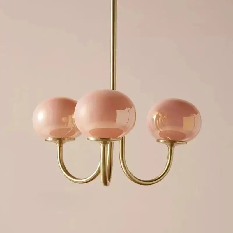 A delicate decorbites designer loft pendant light with soft pink glass globes and polished brass arms for bedroom decor