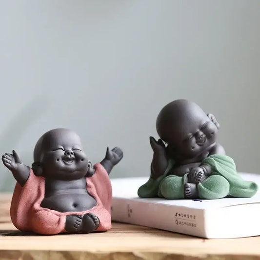 Two ceramic maitreya buddha statue tea sculptures in pink and green robes with smooth matte finishes for living room decor