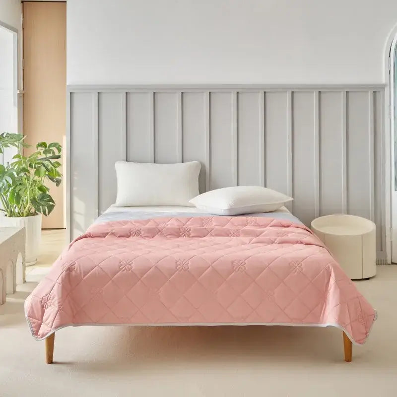 A soft pink quilted cool summer blanket with diamond pattern and white piping for bedroom cooling comfort