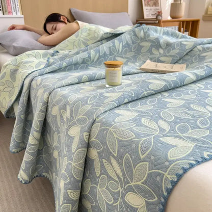 Soft blue quilted decorbites cotton towel blanket with subtle cream and gray leaf pattern and cozy textured surface
