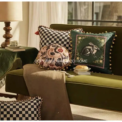 Emerald green velvet cushion cover with embroidered rabbit design and gold-toned pom-pom trim for living room decor