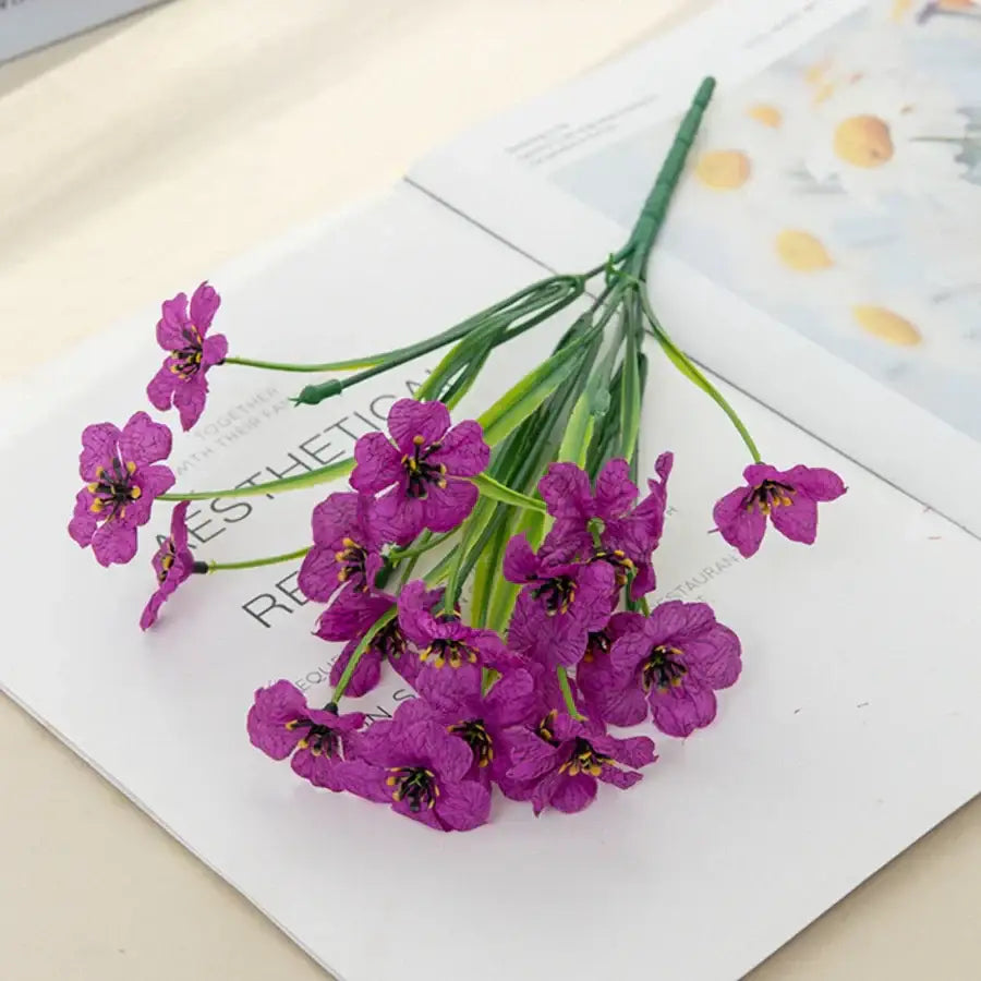 A cluster of artificial purple flowers with green stems designed as a bouquet for artificial cherry blossom wall decor