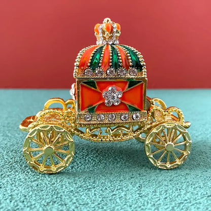 Decorative gold carriage jewelry trinket box with red and green enamel rhinestones and a jeweled crown topper
