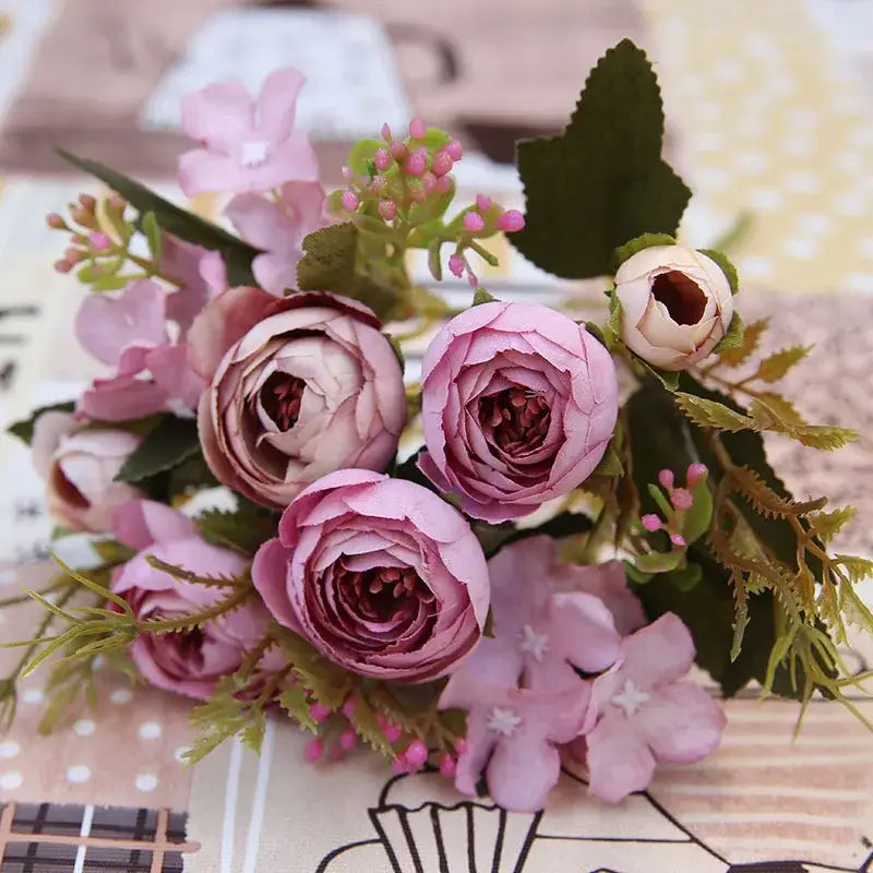 Delicate pink and white silk tea rose ranunculus bouquet with mauve petals and greenery for wedding decor