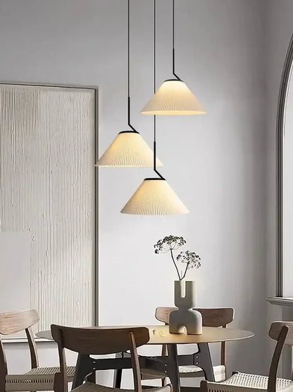 Three cream pleated chandelier pendant lights with black metal fixtures hanging above a dining table decorbites cream led