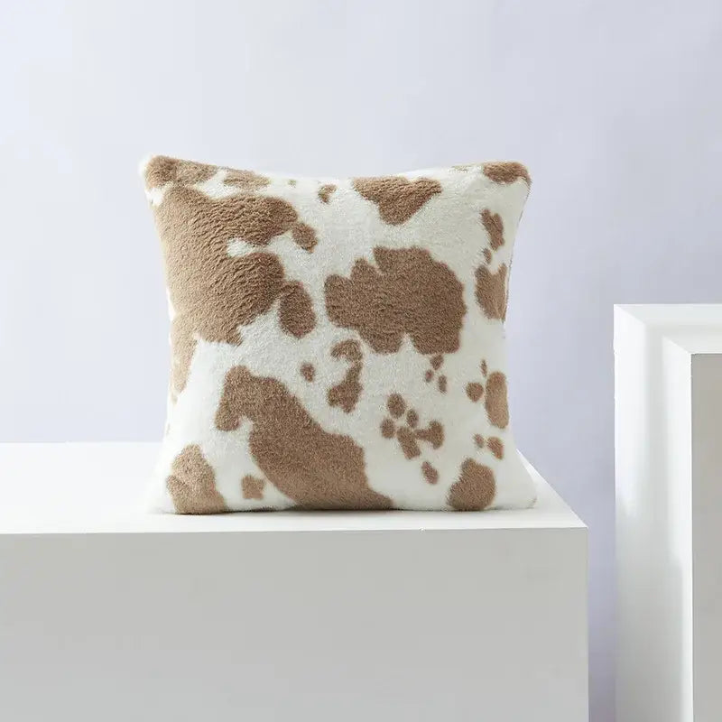 A plush cushion cover with black white flower decorbites design featuring tan and white cow print for living room decor
