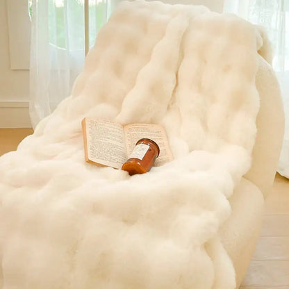 Cream-colored double layer faux fur throw blanket with plush texture draped over armchair decorbites gradient pink