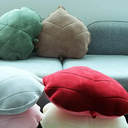 Soft plush leaf shaped throw pillows in sage mustard green beige and pastel shades on a gray couch for living room decorbites 3d leaf