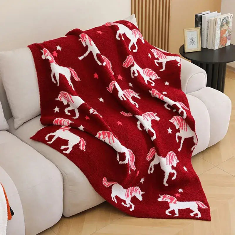 A cozy fleece red unicorn blanket with white unicorns and stars in soft plush knit for bedroom bedding