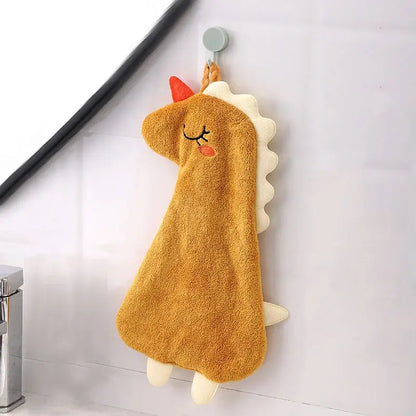 A plush tan unicorn hand towel with red horn and white mane made of double-layer coral velvet hanging from a hook
