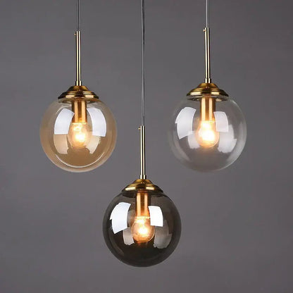 Polished steel glass pendant light trio with brass fixtures and clear amber and smoked glass shades for dining room