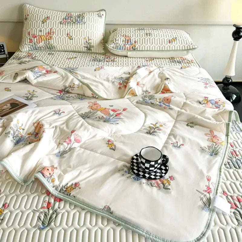 Cream-colored quilted cool comforter set with embroidered pastel flowers and cartoon bunnies in ruffled bedding design