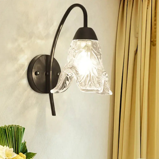 Post-modern black metal wall sconce with a clear crystal shade and intricate textured glass for bedroom use