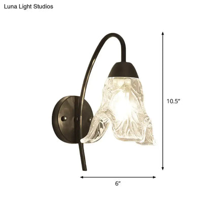 Post-modern black metal wall sconce with a clear crystal shade and textured glass for bedroom lighting