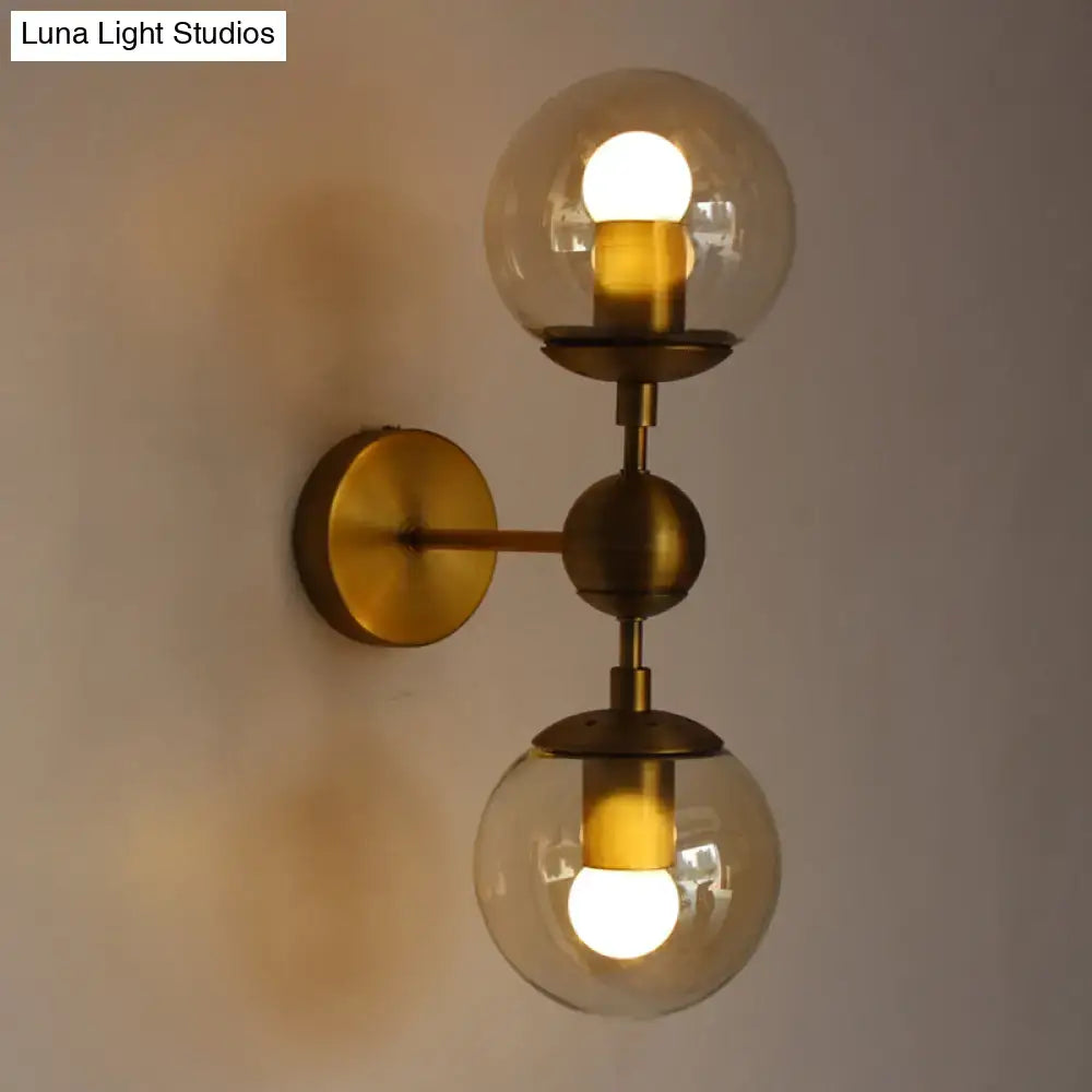 Post modern brass wall light with amber glass and two illuminated spherical e26 e27 bulbs for bedroom use