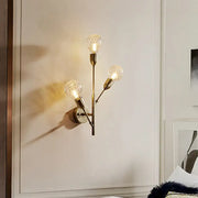 Post-modern brass wall light fixture with three illuminated clear lattice glass bulbs for bedroom use