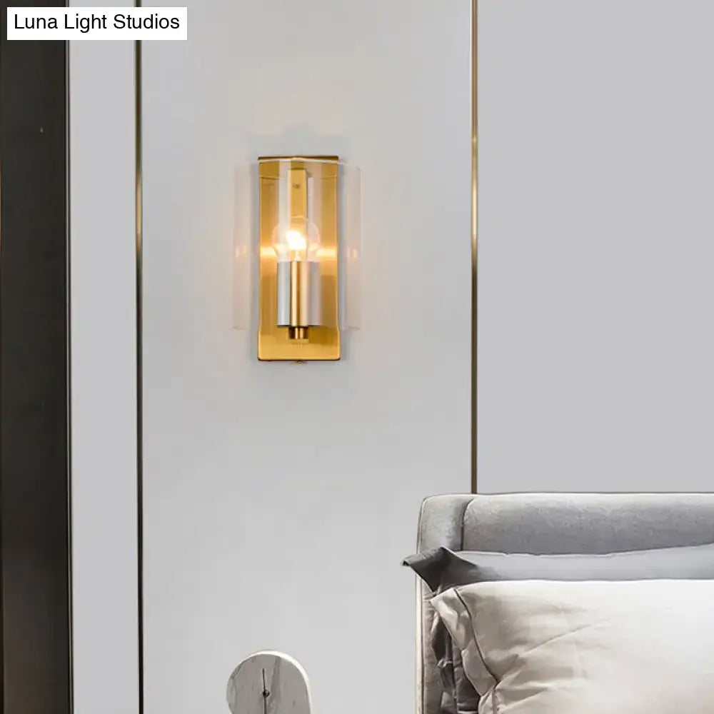 Post modern brass wall sconce with gold-toned clear textured white glass and cylindrical metallic accents for bedroom lighting