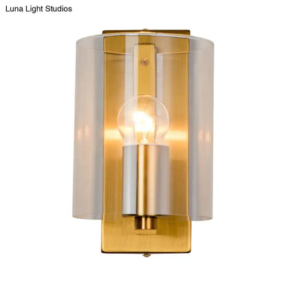 Post modern brass wall sconce with gold-toned finish frosted glass cylinder and clear textured white light for bedrooms