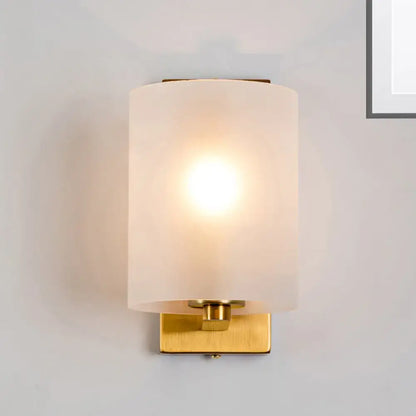 Post modern brass wall sconce with warm clear textured white cylindrical frosted glass for bedroom lighting