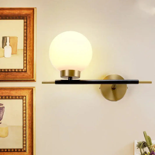 Post-modern white and brass sphere wall sconce with frosted glass globe and black accents for bedroom lighting