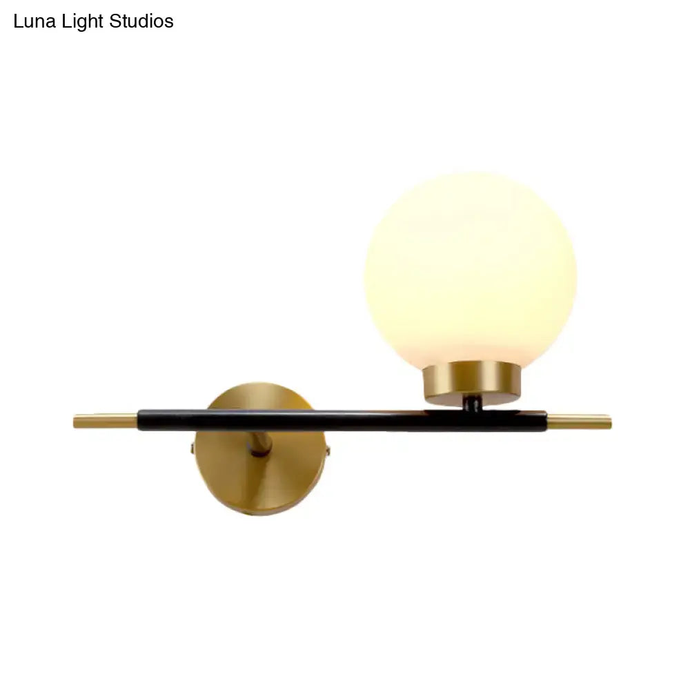 Post-modern sphere wall sconce with matte black bar gold-toned accents and frosted glass globe for bedroom lighting
