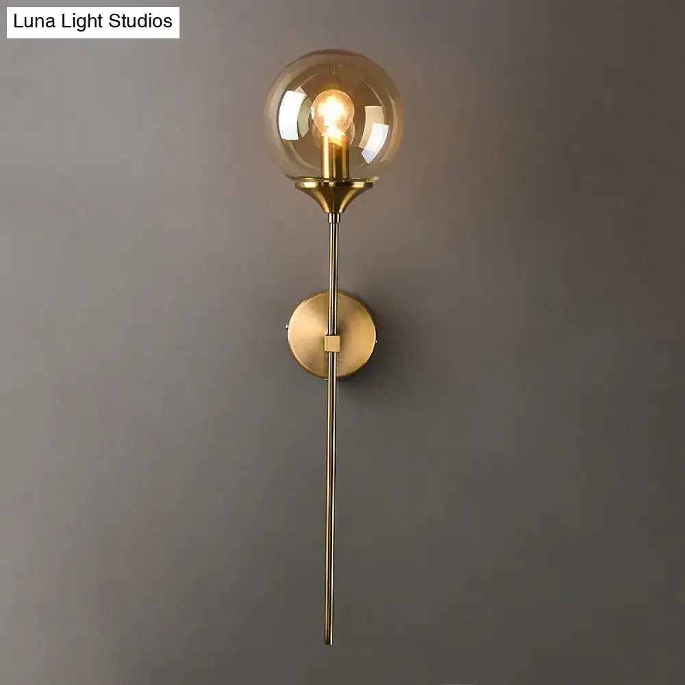 A sleek brass postmodern wall sconce with amber and smoke grey glass globe featuring an e27 bulb socket