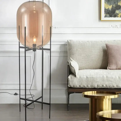 Postmodern floor lamp with amber glass ball and slender black metal legs suitable for living room decorbites glass ball