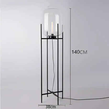 A sleek black metal floor lamp with a clear glass ball dome housing an exposed filament bulb for modern decorbites decor
