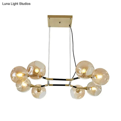 Modern gold-toned DecorBites™ postmodern island lighting with amber ball glass globe shades and adjustable black cords