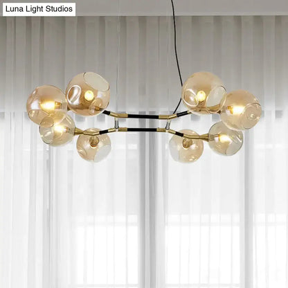 Modern gold-toned DecorBites island lighting featuring amber ball glass globes and black structural accents with adjustable cord